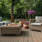 Nowoczesne meble ogrodowe z technorattanu na tarasie, zestaw wypoczynkowy z sofą, fotelem i stolikiem, w tle ogród z kwiatami.